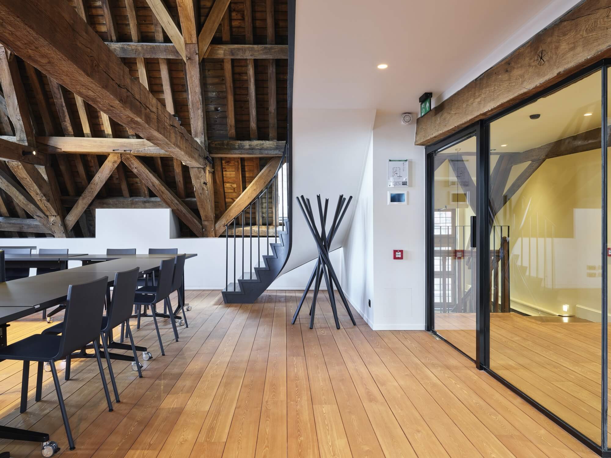 Office space with exposed wood ceiling, hardwood flooring, and glass room dividers.