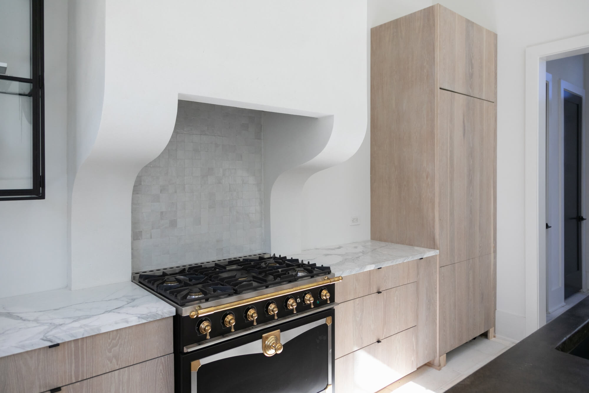 Light and bright kitchen design with light oak cabinets and a black range.