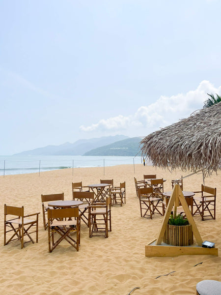 Several seating areas with furniture made from recycled materials sitting on a beach in Vietnam.