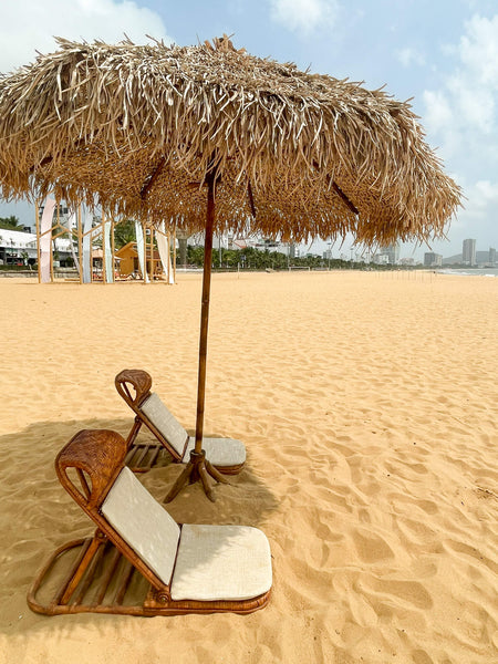 Two reclining beach chairs and an umbrella crafted using recycled materials.