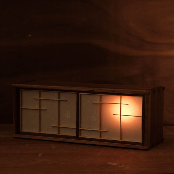 A tea cabinet made from wood with an interior light designed to resemble the silhouette of the moon.